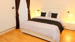 Een opgemaakt bed met zwart-wit beddengoed, twee bedlampjes en een houten vloer.