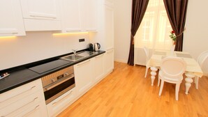 Een moderne keuken met witte kasten, een zwart aanrecht en een eethoek met een tafel en stoelen.