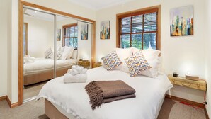 Une chambre à coucher avec un grand lit, une table de chevet, un miroir et des œuvres d’art accrochées au mur.