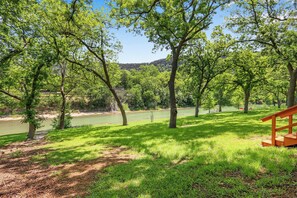 Un parc avec un lac, des arbres et un banc en bois.