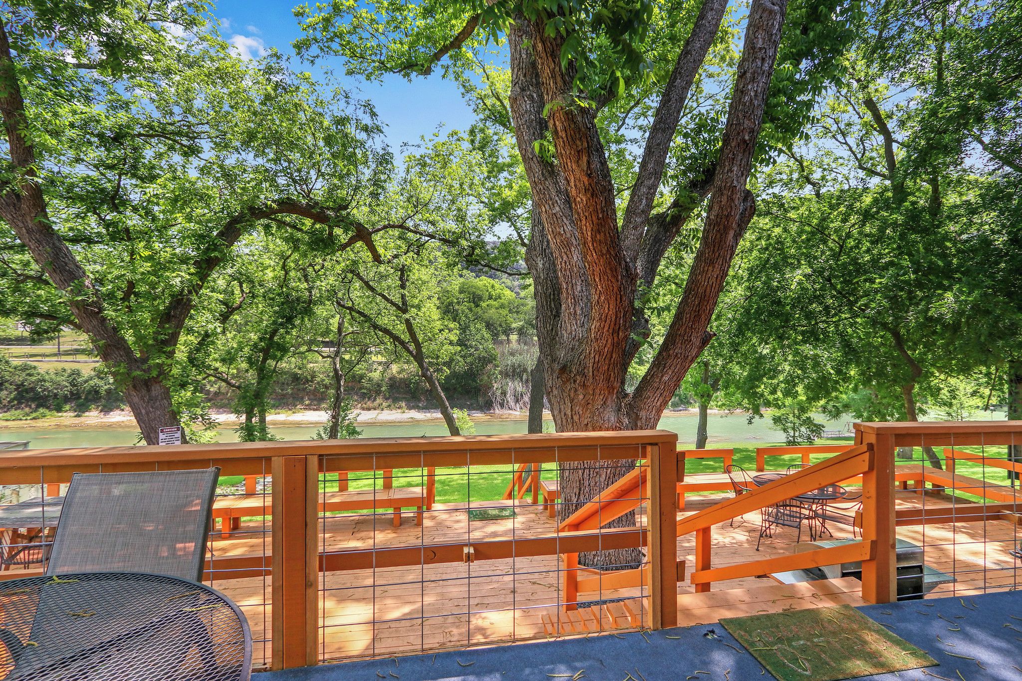 An outdoor deck with wooden railings, seating, and a view of a lake.