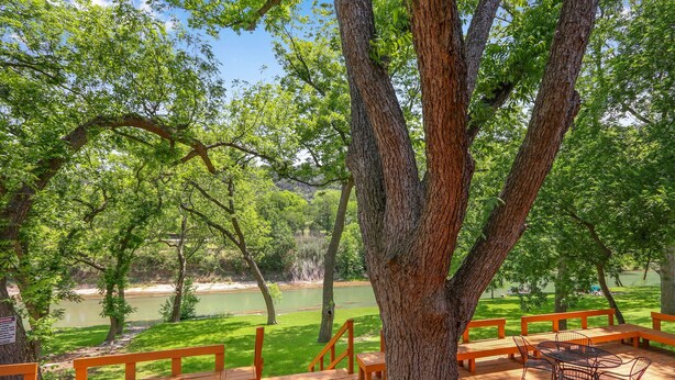 Une terrasse en bois avec des bancs et une table, donnant sur une rivière.
