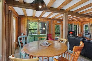 Een houten interieur met een ronde tafel, stoelen, een groen kastje en een bordje met de tekst 'Hill Country Premier Lodging'.