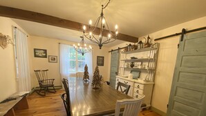 A dining room with a wooden table, white chairs, a chandelier, and a rustic decor. - Luxurious Farmhouse Style Home - Get away from it all in picturesque setting (Brownfield)