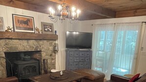 A cozy living room with a stone fireplace, leather sofa, wooden coffee table, and a television on a cabinet. - Luxurious Farmhouse Style Home - Get away from it all in picturesque setting (Brownfield)