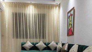 A living room with a green sofa, a coffee table, and a painting on the wall. - Tidy and Calm appartment  equiped with WiFI  close to airport and ocean (Tanger)