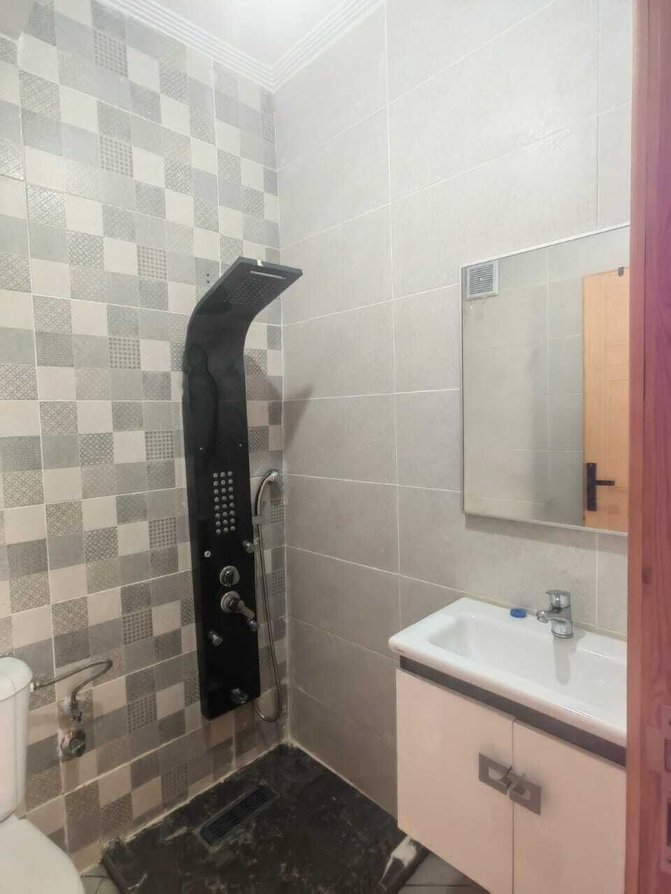 Un baño con ducha, lavamanos y espejo.