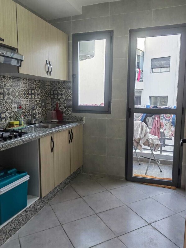 A kitchen with a tiled backsplash, a window, and a sliding glass door leading to an outdoor area.
