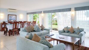 Amplia sala de estar con sofás azul claro y una mesa de comedor preparada para cuatro personas.