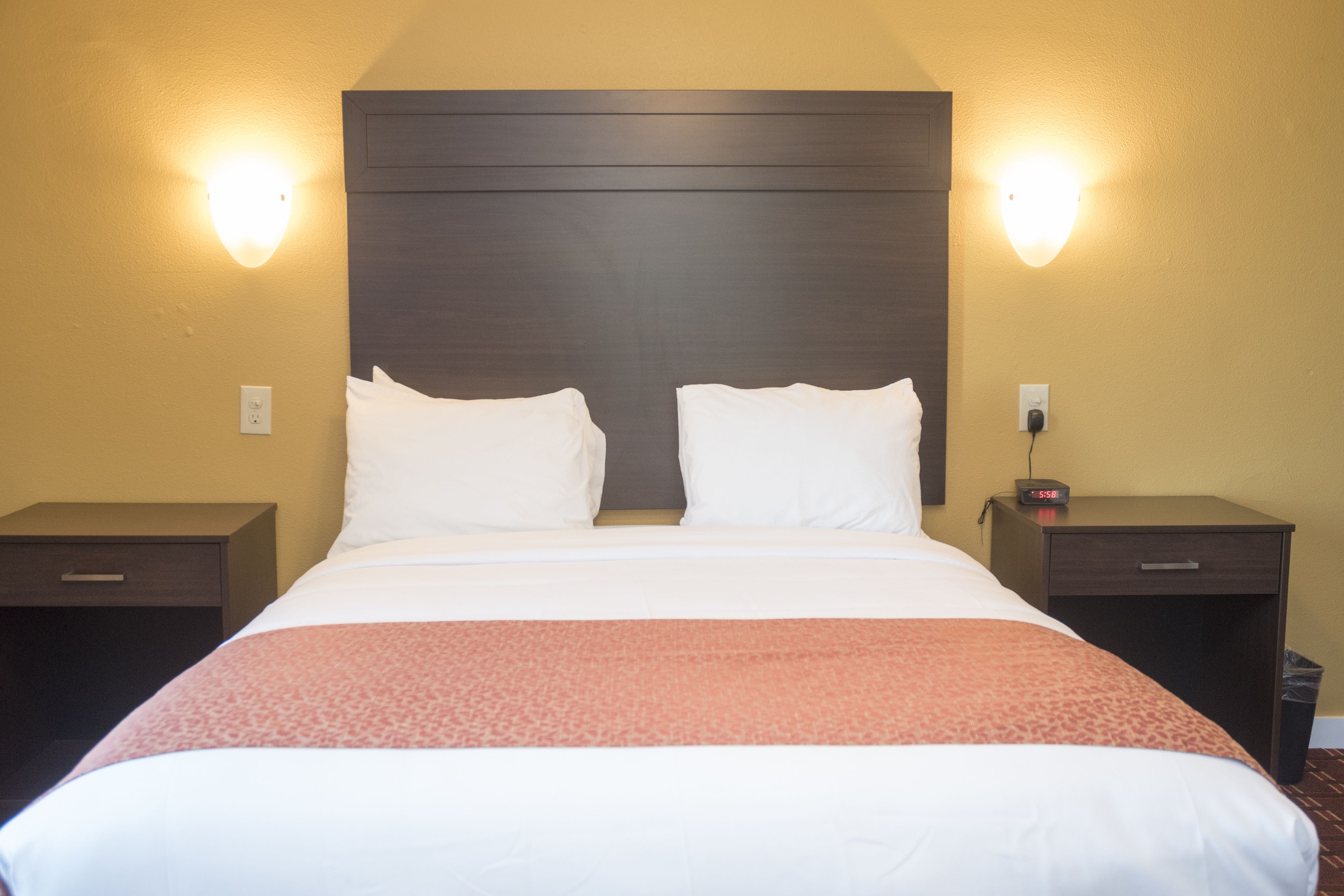 Habitación de hotel con una cama grande, dos mesitas de noche y una lámpara de pared.