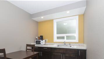A compact kitchen with a microwave, sink, and a small dining area with a table and chair.