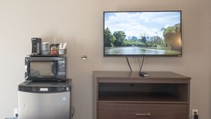 A kitchenette with a microwave, coffee maker, and a TV mounted on the wall. - Capitol Hill Motel (Portland)