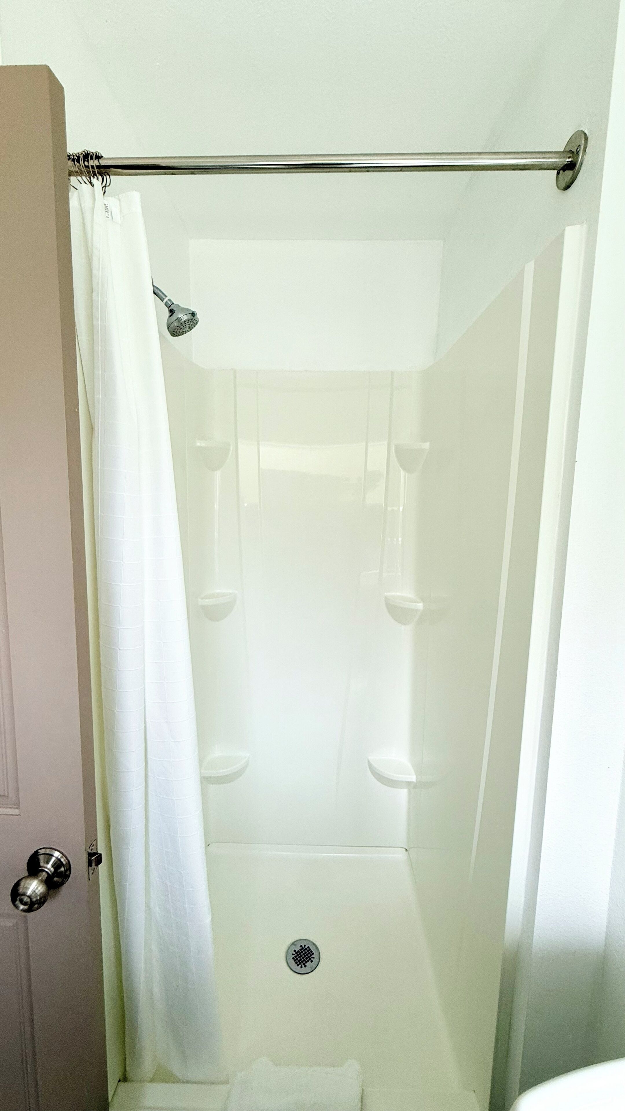 Eine Dusche mit Glastür, Duschkopf und Handtuchhalter.