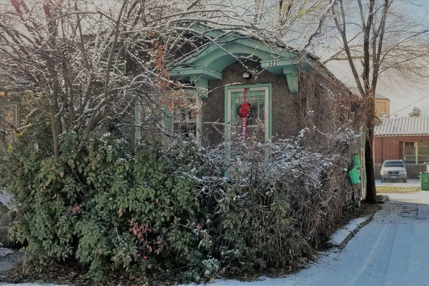 A building with a green facade, a red door, and a number '322' above it.