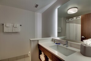 A modern bathroom with a large mirror, a sink, and a towel rack.