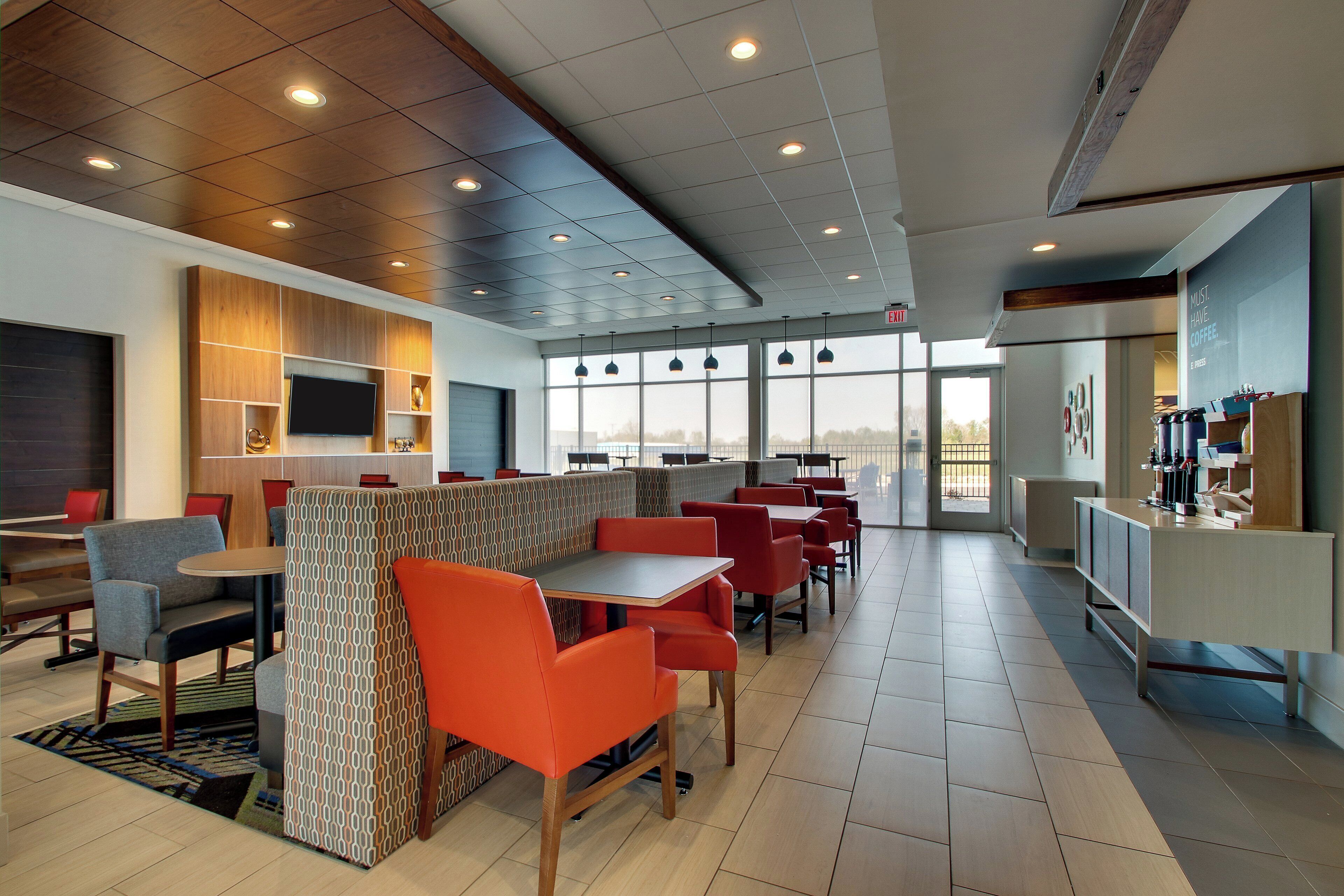 A modern restaurant with high ceilings, recessed lighting, and a mix of seating options including booths and tables.