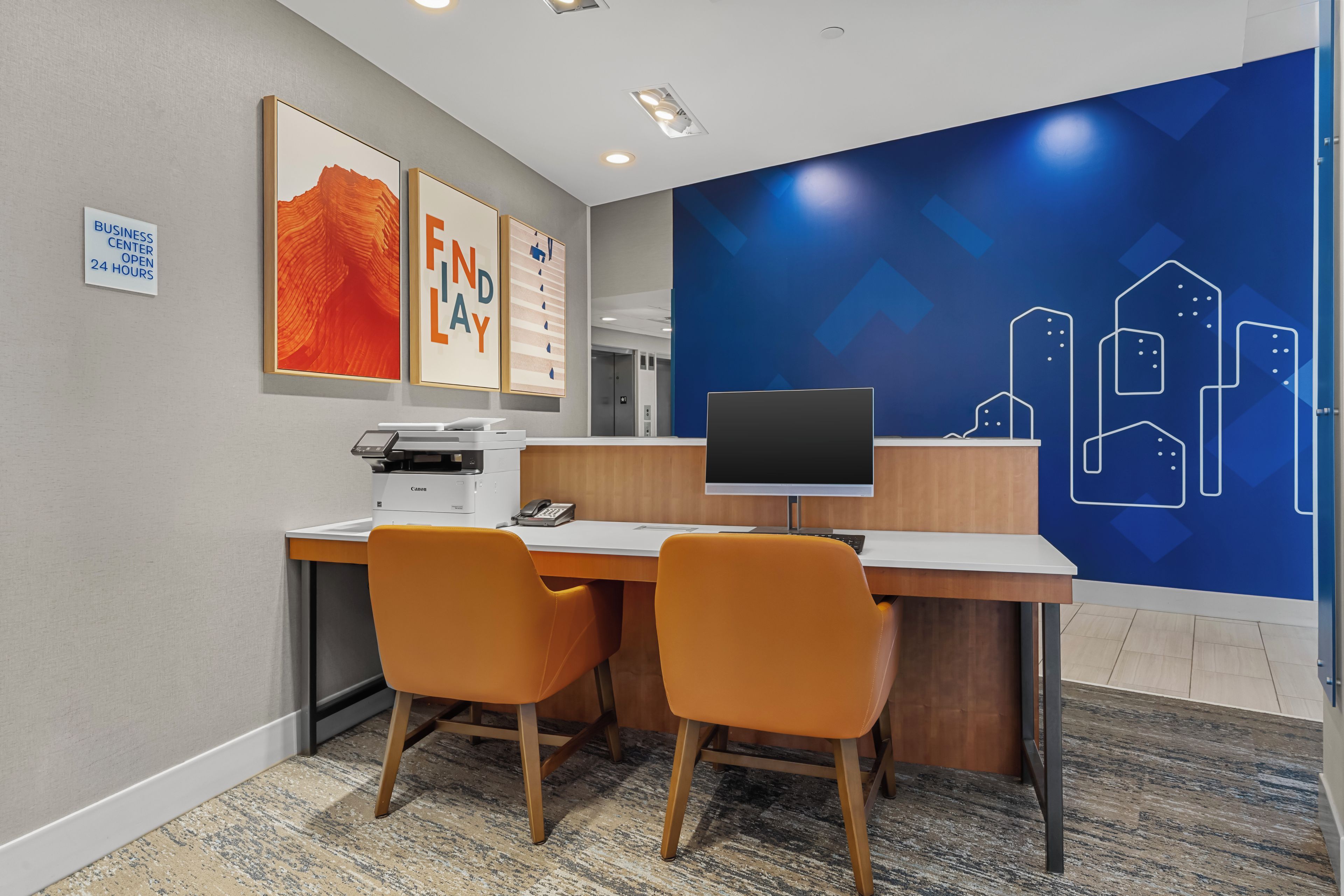 A business center with a desk, two chairs, a printer, and a computer monitor.