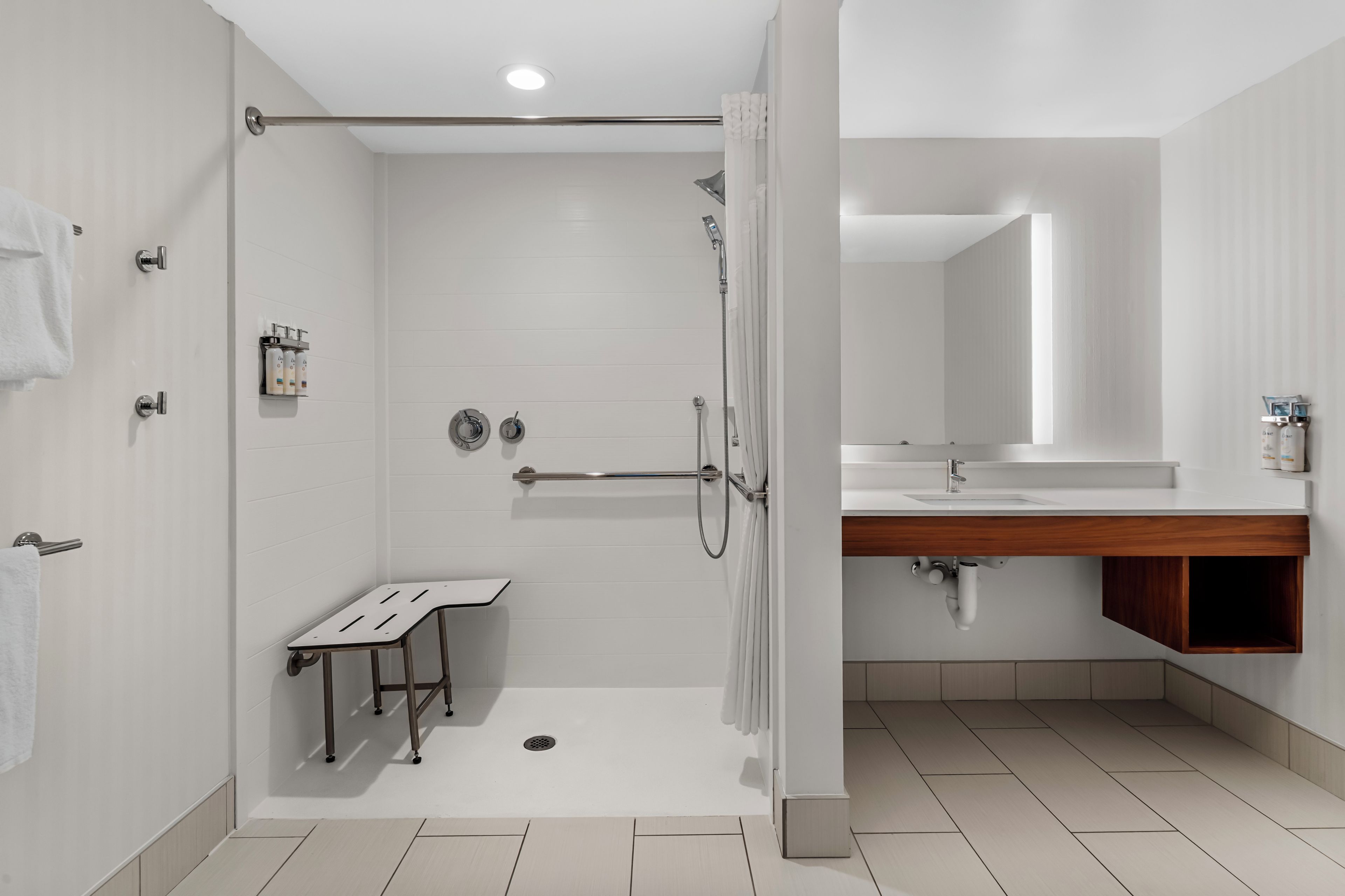 Un baño moderno con cabina de ducha, inodoro y lavabo con tocador de madera.