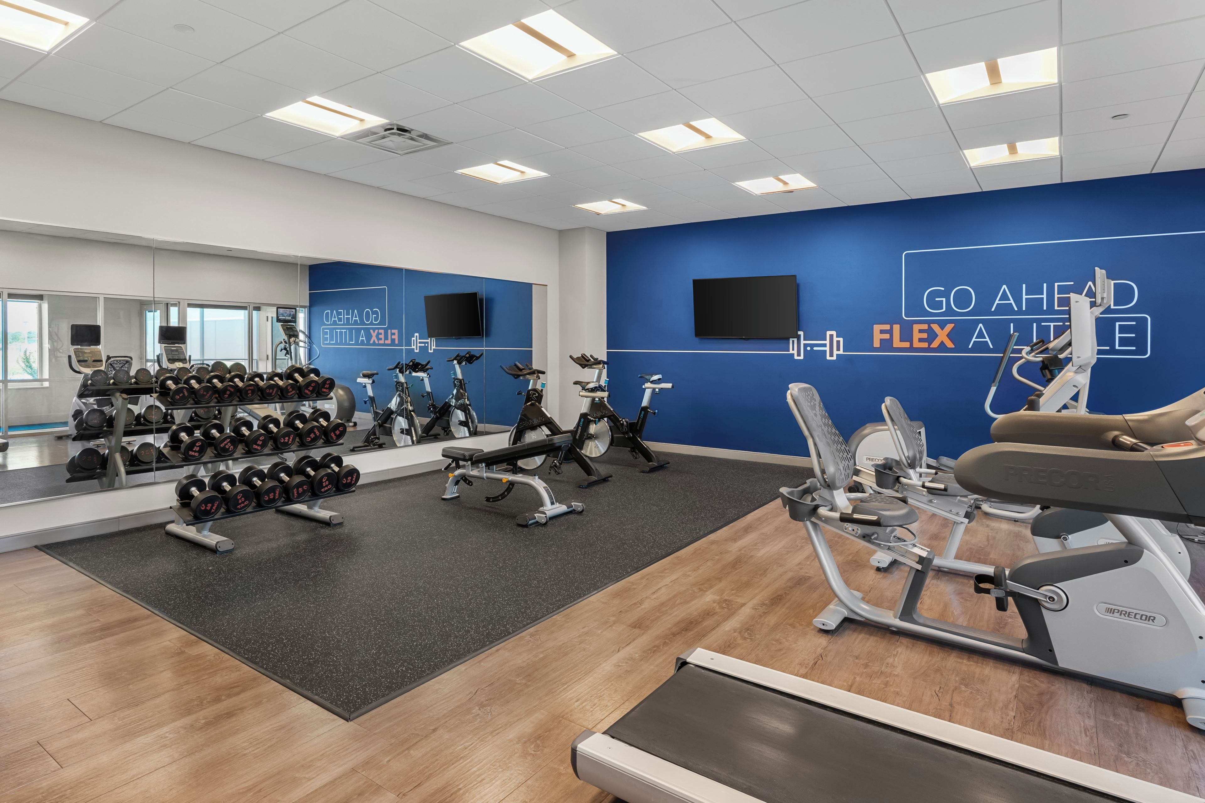 A gym with exercise equipment, a mirrored wall, and motivational wall art.