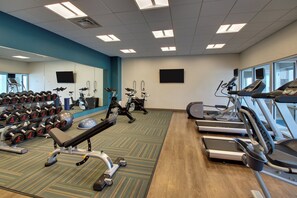 A gym with treadmills, stationary bikes, and free weights.