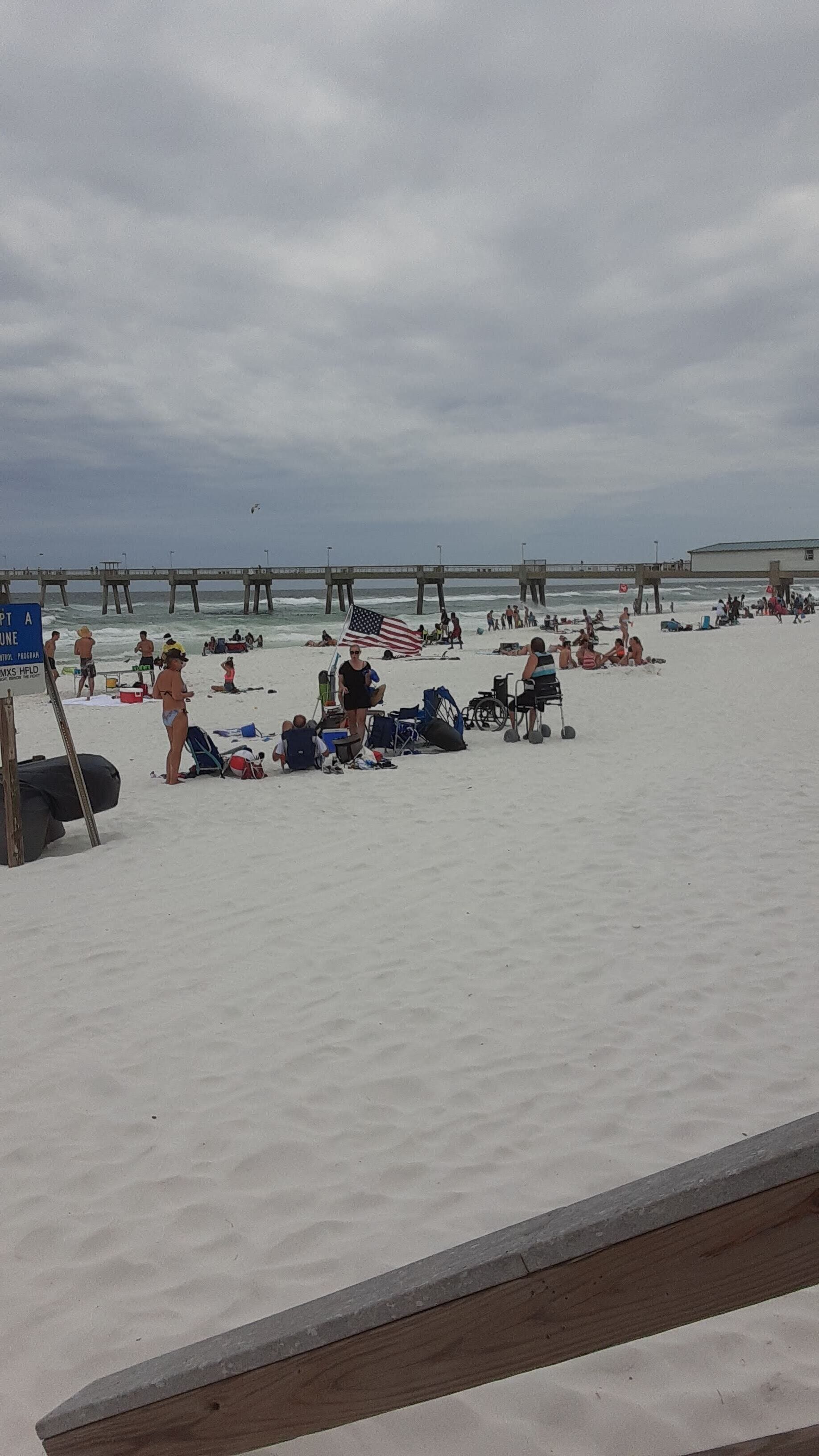 A beach with people, a pier, and a lifeguard stand.