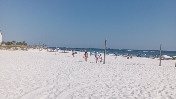 A sandy beach with footprints, a clear sky, and a few people in the distance. - Gipson Inn Motel (Fort Walton Beach)
