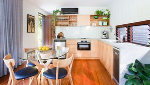 Une cuisine moderne avec des meubles en bois, une table à manger en verre et un four encastré.