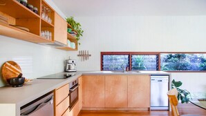 Une cuisine moderne avec des meubles en bois, un lave-vaisselle encastré et une grande fenêtre donnant sur un paysage verdoyant.