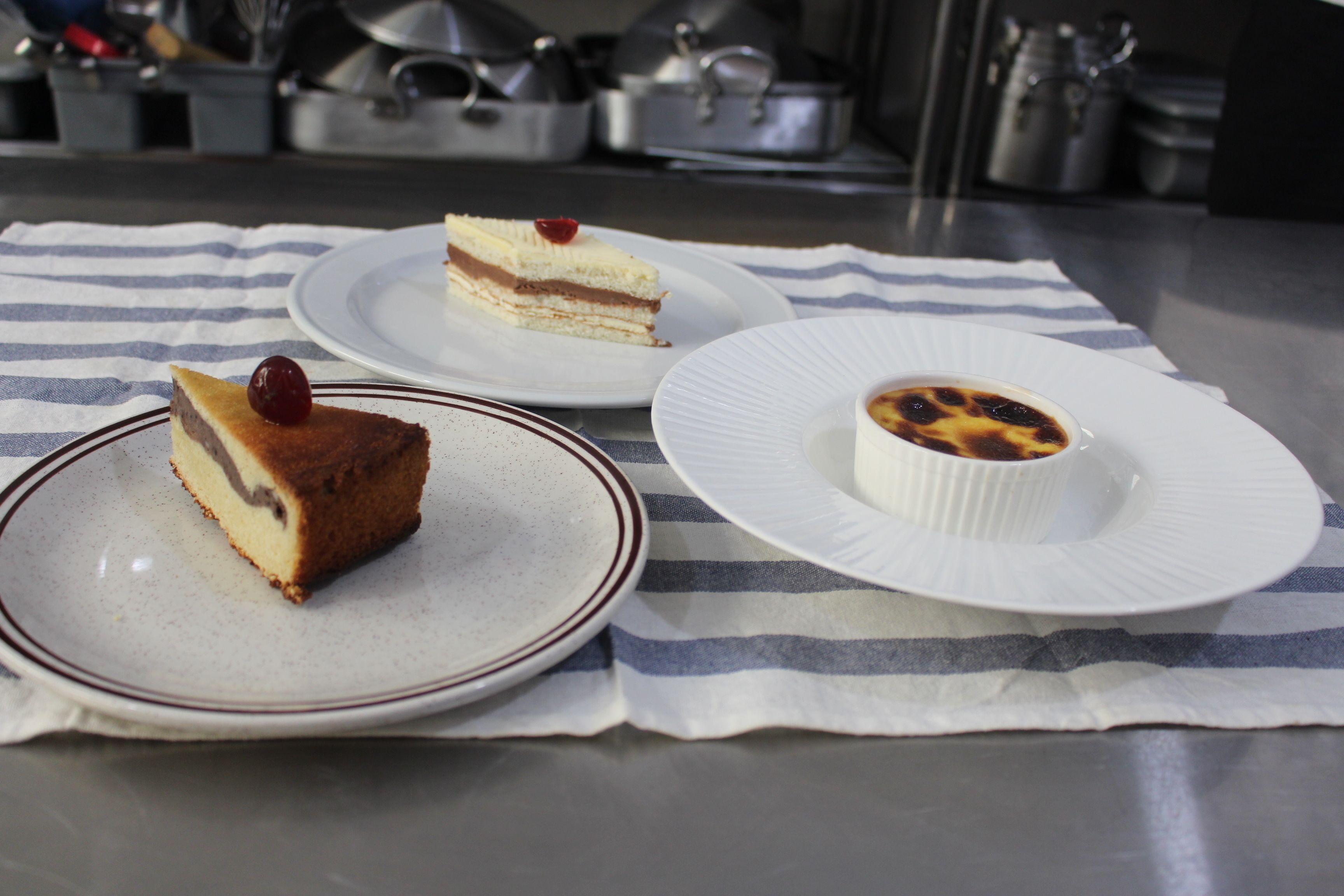 Three plates of dessert on a striped cloth.