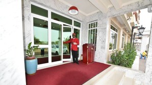 Een hotelingang met een rode loper, een beveiligingsbeambte en een rood podium.