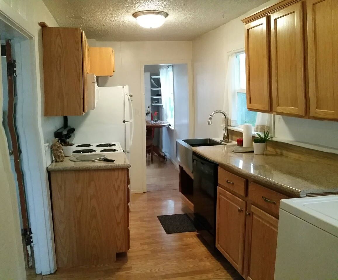 A compact kitchen with wooden cabinets, a white refrigerator, a stove, and a sink.