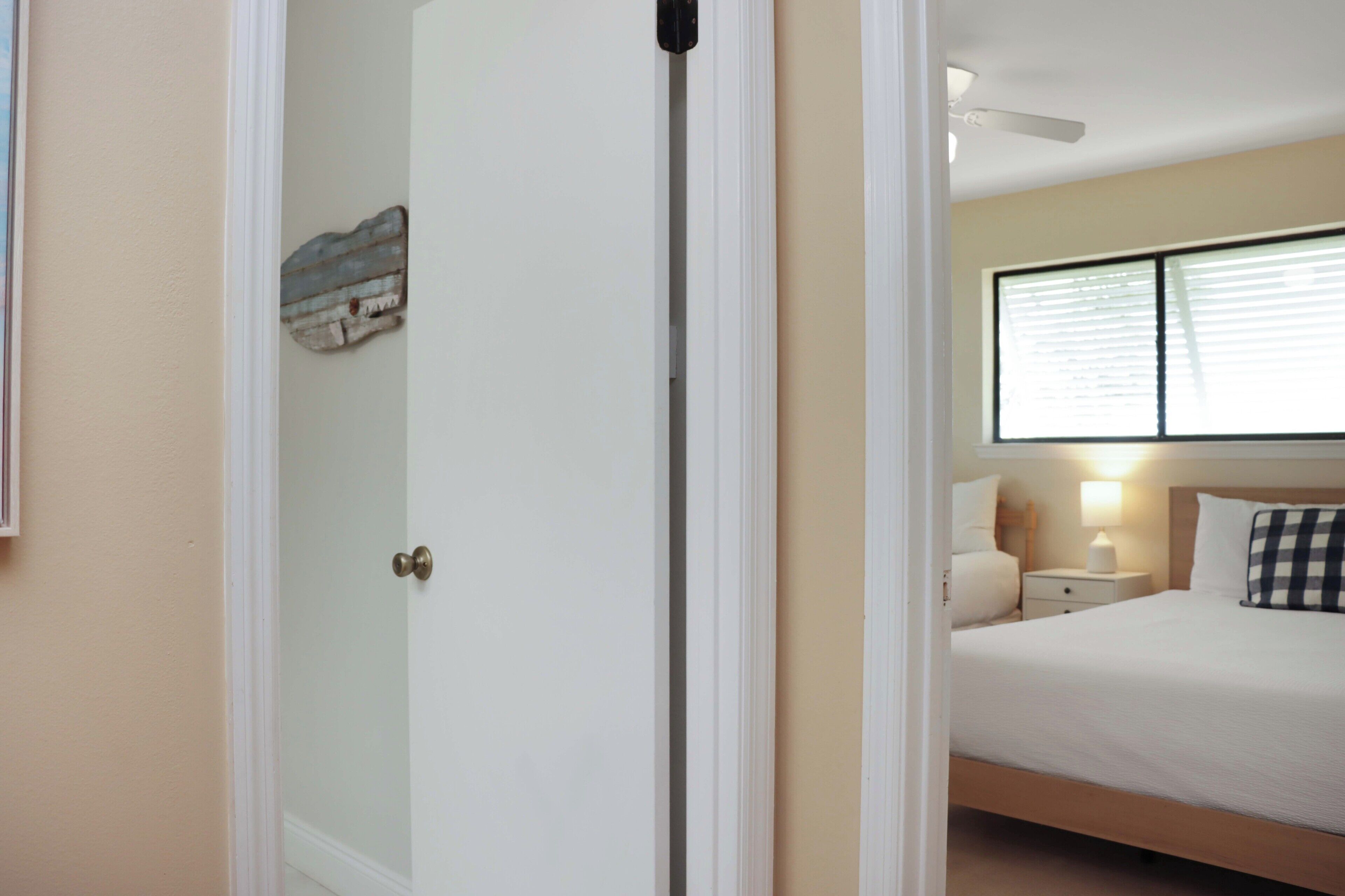 Un dormitorio con cama, mesita de noche, lámpara y ventana con persianas.