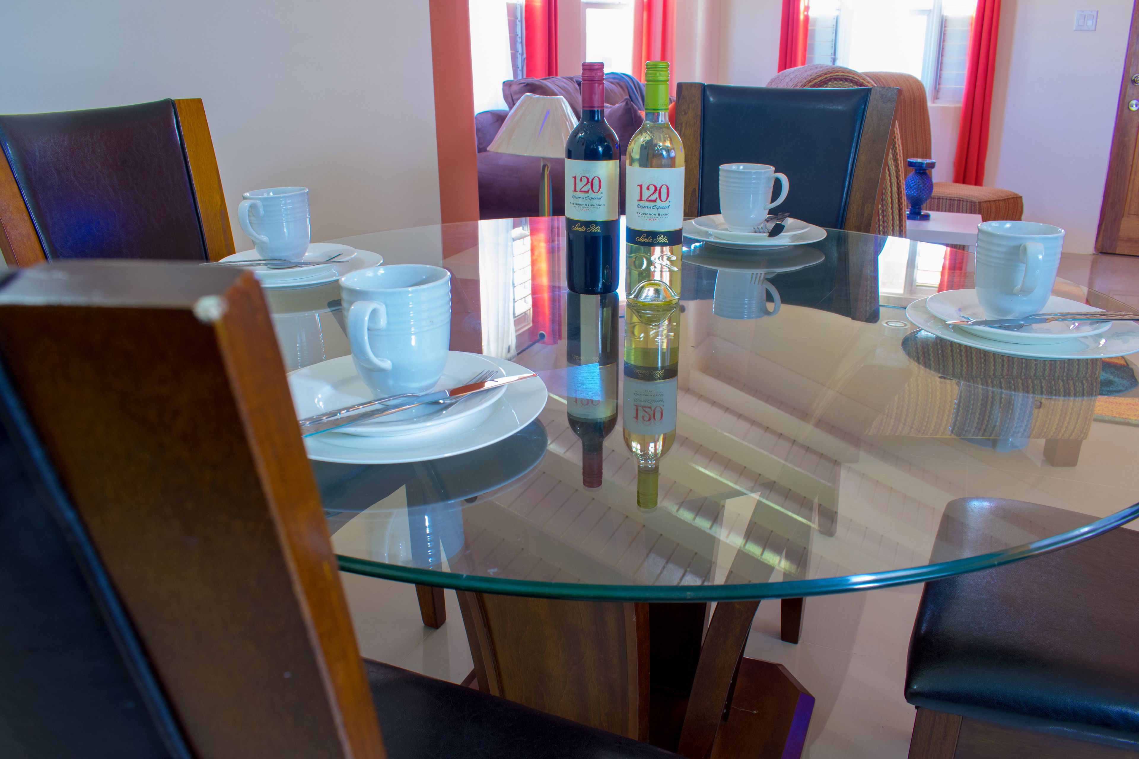 A dining area with round glass tables, chairs, and a variety of tableware including plates, cups, and cutlery.
