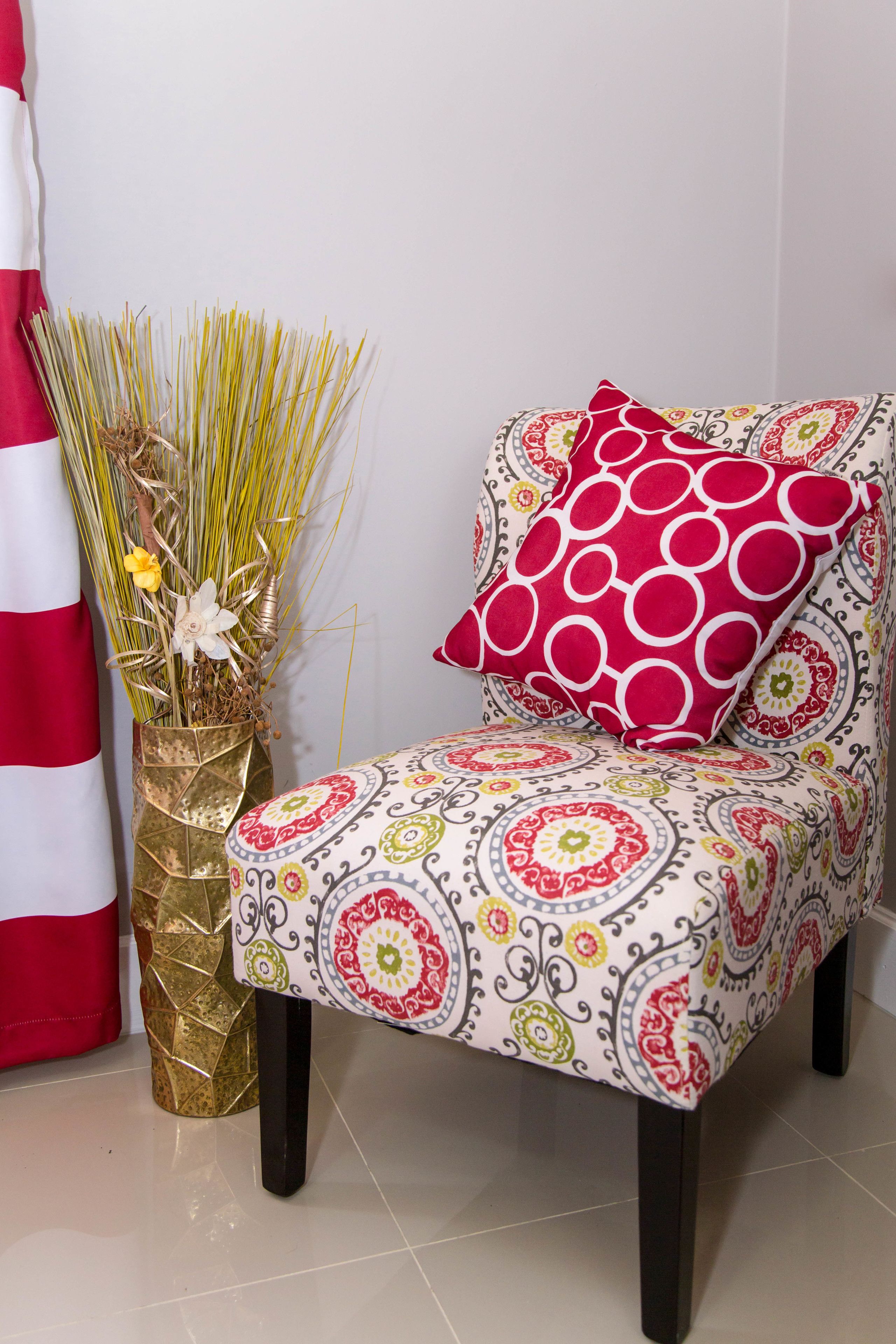 Une chaise avec un coussin à motifs et un vase décoratif contenant des plantes séchées.