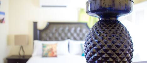 Gros plan d’un vase bleu à la texture particulière, posé sur une table, avec une chambre d’hôtel floue en arrière-plan.