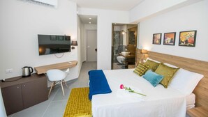 Une chambre d’hôtel avec un lit, un bureau, une télévision et des œuvres d’art accrochées au mur.