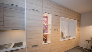 Une cuisine moderne avec des meubles en bois, des étagères intégrées et un plan de travail blanc.