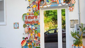 Une entrée d’immeuble agrémentée de décorations colorées et d’une enseigne sur laquelle on peut lire « Il Muro Vecchio ».