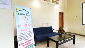 A reception area with a blue sofa, a glass-top table, and a banner advertising a VIP card. - Wisma Gading Indah (Jakarta)