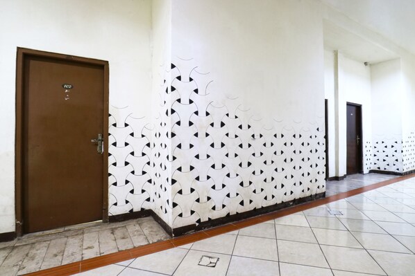 A hallway with a patterned wall, a brown door labeled '102', and a tiled floor. - Wisma Gading Indah (Jakarta)