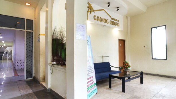 A reception area with a blue sofa, a coffee table, and a wall-mounted sign reading "GADING INDAH". - Wisma Gading Indah (Jakarta)
