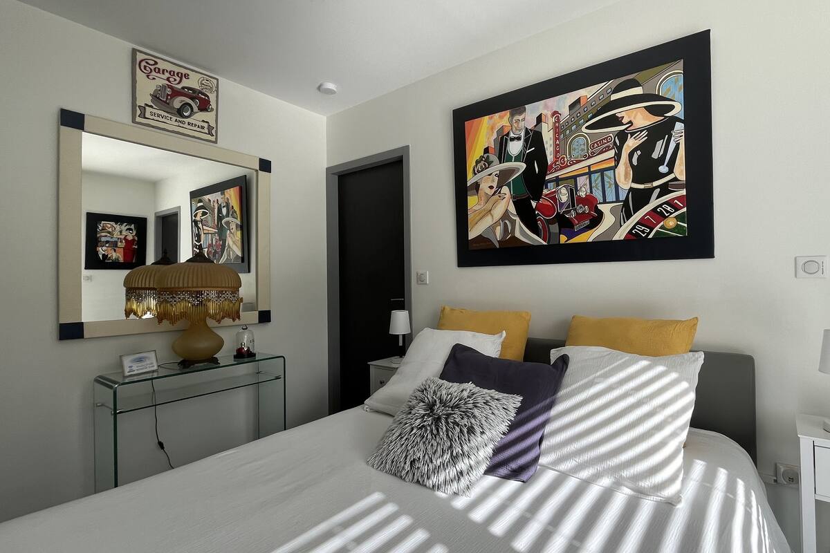 Un dormitorio moderno con una cama grande, una mesita de noche, una lámpara y un cuadro colgado en la pared.
