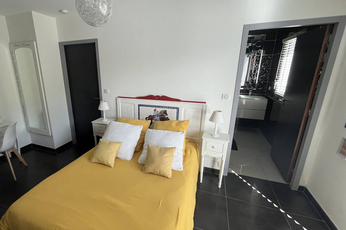 Una habitación de hotel con cama, escritorio, silla, espejo y puerta.