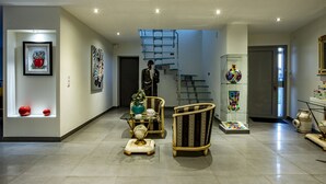 A modern interior with a staircase, framed artwork, and decorative chairs. - Domaine Georges V (Saint-Junien)