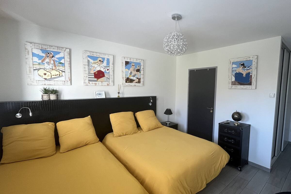 Habitación de hotel con dos camas, una mesita de noche, una lámpara, un aparador y obras de arte en las paredes.