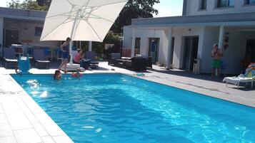 Una piscina al aire libre, sillones reclinables de piscina