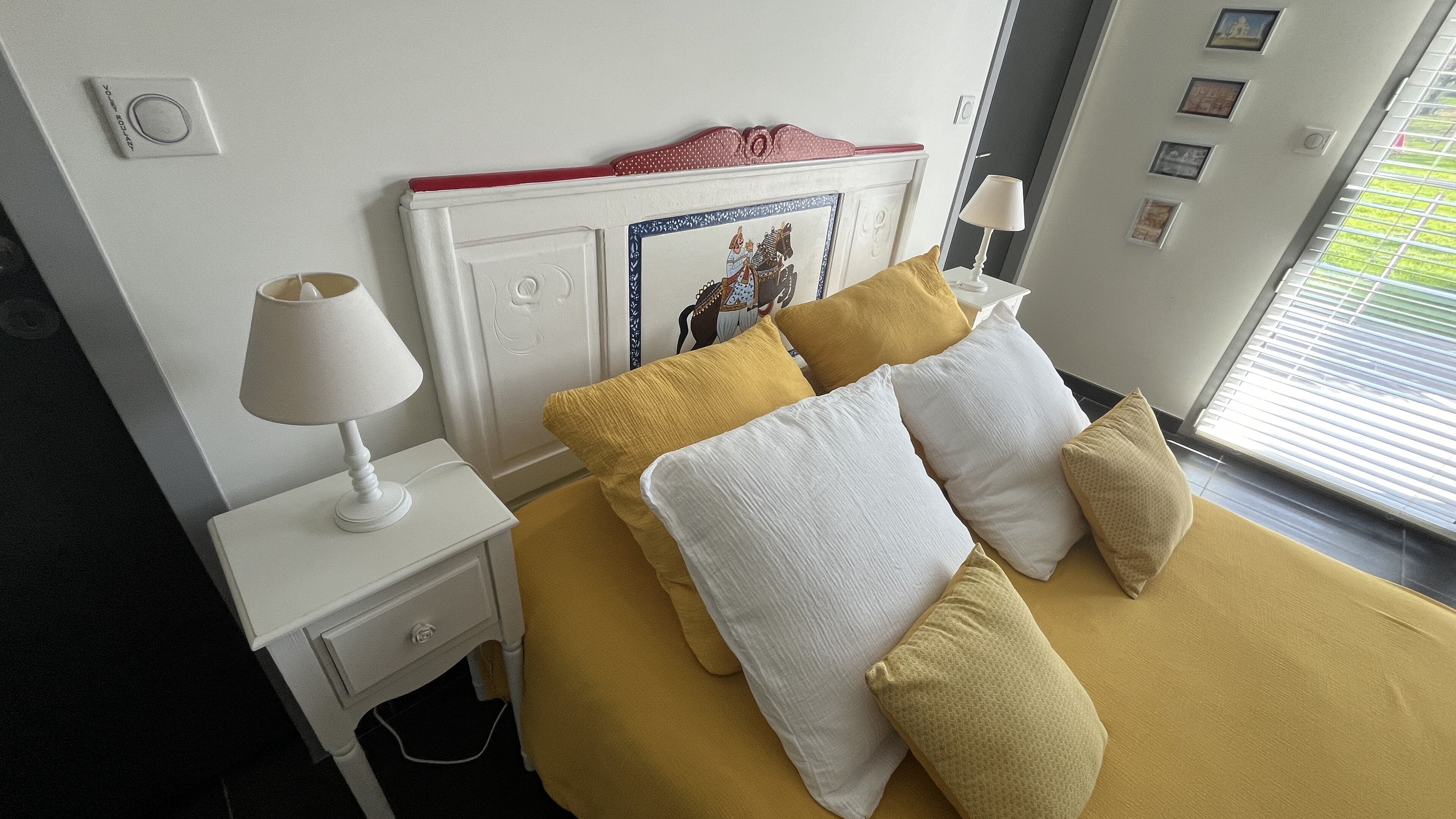 Una habitación de hotel con una cama, una mesita de noche blanca y una lámpara.