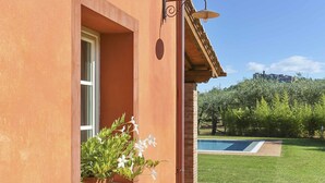 A building with a window, a wall-mounted light fixture, and a view of a swimming pool and garden. - Wonderful private villa with A/C, WIFI, private pool, TV, veranda and panoramic view, close to L... (Colle Di Compito)