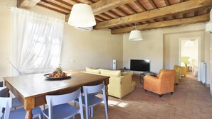 A cozy living room with a wooden ceiling, a television, a sofa, and a dining table with chairs. - Wonderful private villa with A/C, WIFI, private pool, TV, veranda and panoramic view, close to L... (Colle Di Compito)
