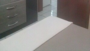 Um quarto com armário, cama e porta aberta para outro espaço.